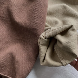 Close-up of twill cotton fabric texture and hem detail in brick red and beige colors