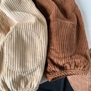 Detail of children's corduroy trousers showing striped texture and oval patch pockets