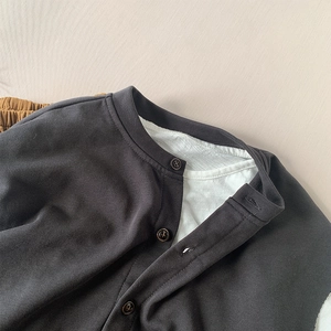 Flat lay detail of child's dark grey cotton vest layered over a white t-shirt