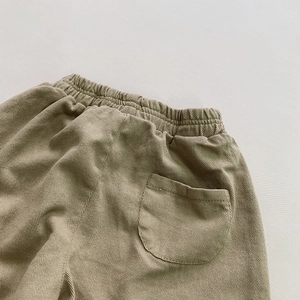 Detail of children's khaki cotton pants featuring elastic waist and back pocket stitching