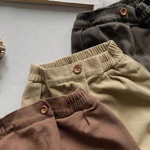 Detail of girls corduroy trousers featuring elastic waistband and vintage wooden buttons
