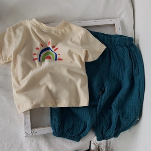 Détail d'un ensemble en coton pour enfant avec t-shirt beige imprimé et pantalon gaufré vert