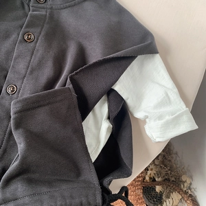 Detail of grey kid's layered vest with vintage wood buttons and soft cotton sleeves