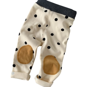 Polka dot baby leggings with yellow knee patches and elastic waistband on white background