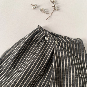 Détail d'un pantalon en coton et lin à rayures avec taille élastique et boutons