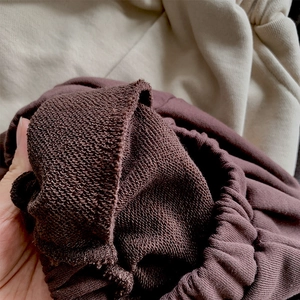 Vue détaillée du tissu en coton bouclé marron foncé et de la finition bord-côte