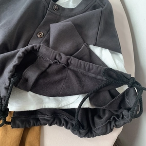 Detail of dark grey cotton vest showing button collar and adjustable drawstring hemline