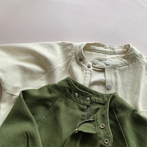 Gros plan des vestes pour enfants en beige et vert olive montrant la texture en sergé de coton