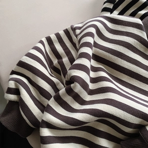 Detailed close-up of brown and white striped fleece fabric with ribbed cuffs texture
