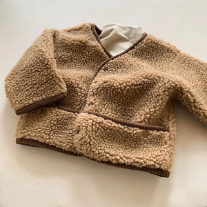 Vue détaillée d'une veste en polaire sherpa marron avec col en V et boutons-pression