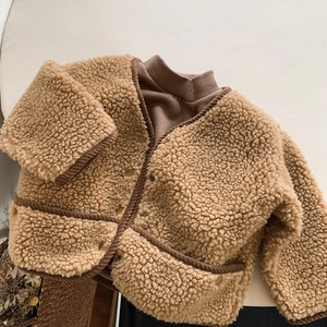 Détail d'une veste en polaire pour enfant avec col en V, passepoil en velours et peluche camel