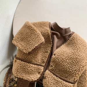 Détail d'un gilet en peau lainée camel avec passepoil marron et texture douce et pelucheuse
