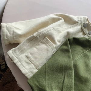 Détail de la texture en sergé de coton et pressions métalliques sur vestes enfants
