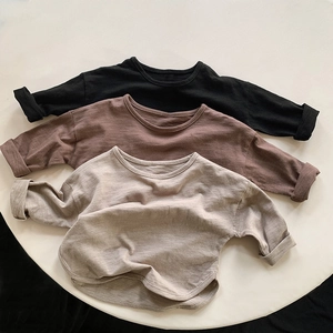 Detail of three long-sleeve slub cotton T-shirts in earth tones on a white platform