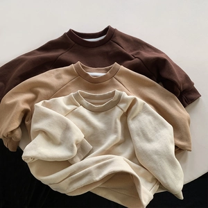 Close-up of three long-sleeved ribbed crewneck sweatshirts in earth-tone colors