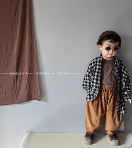 Kids' retro outfit with plaid shirt, brown t-shirt, and corduroy pants in an indoor setting