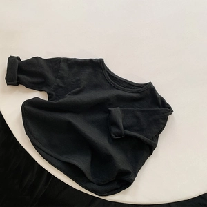 Detail of a minimalist black long-sleeve cotton T-shirt featuring slub cotton texture fabric