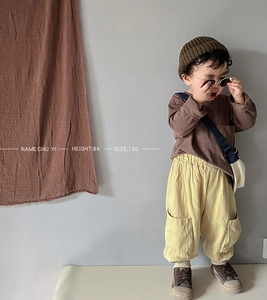 Detail of child wearing a long-sleeved brown cotton T-shirt and loose yellow cargo pants