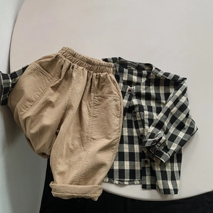Flat lay of kids plaid cotton shirt and khaki casual pants on a grey round table