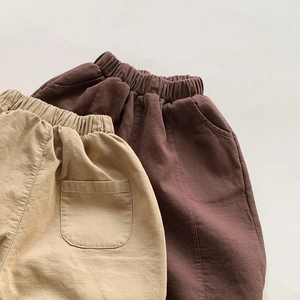 Flat lay detail of kids relaxed fit cotton trousers in khaki and dark brown colors