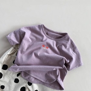 Détail d'un t-shirt violet pour enfant avec emoji cœur et pantalon blanc à pois noirs
