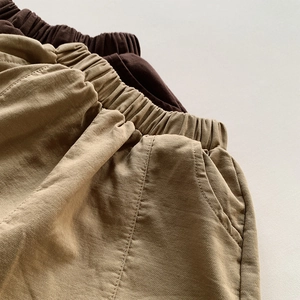Detail of high-elastic waistband and side pockets on kids relaxed fit cotton trousers