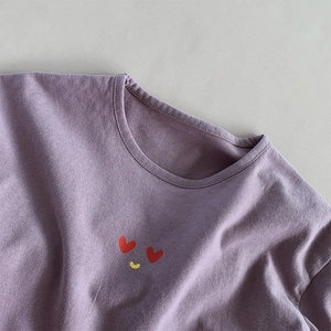 Détail du tissu en coton violet doux avec un graphique de sourire en cœur sur le col