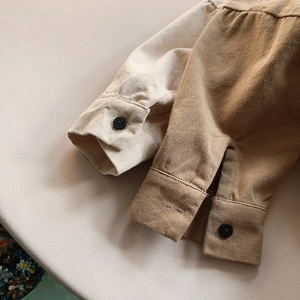 Close-up of children's cotton shirt cuffs in beige and khaki with matte black buttons