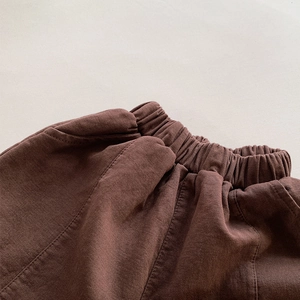 Close-up of deep brown cotton twill fabric with elastic waistband and neat stitching details