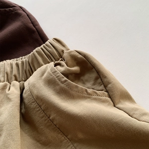 Detail view of elastic drawstring waistband and side pockets on khaki cotton pants