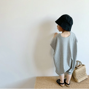 Back view of a girl in loose grey cotton romper with black bucket hat and woven bag