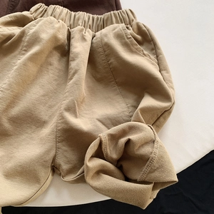 Detailed close-up of beige twill cotton trousers showing elastic waistband and texture