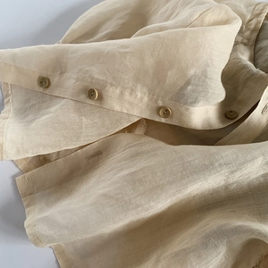 Vue détaillée du tissu en lin beige respirant avec boutons marron de haute qualité