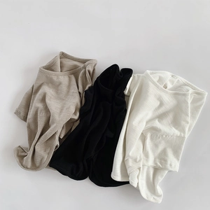 Trois T-shirts respirants en coton flammé en beige, noir et crème posés à plat