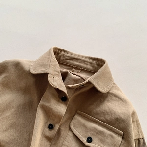 Detailed macro view of khaki cotton twill shirt fabric with black buttons and flap pockets