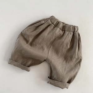 Detail of loose linen shorts featuring an elastic waistband and folded cuffs in khaki