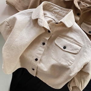 Close-up of cream cotton shirt texture with chest pocket and black buttons detail