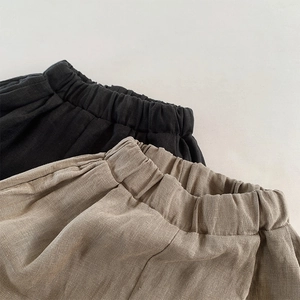 Detailed close-up of natural linen fabric texture and elastic waistband on kids shorts