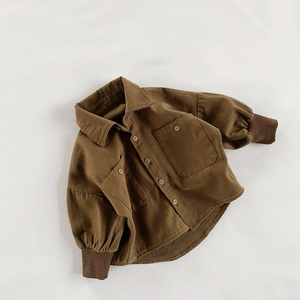 Detail of dark brown corduroy kids shirt featuring large utility pockets and ribbed cuffs