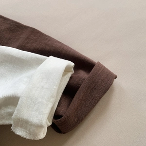 Close-up of white and brown slub cotton T-shirt sleeves showing fine waffle texture