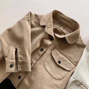 Close-up of khaki cotton kids shirt featuring twill texture and single chest pocket