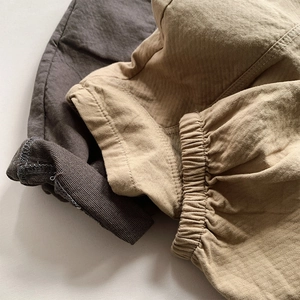 Detail of ribbed elastic cuffs on kids' cotton sweatpants in dark grey and khaki colors