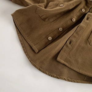 Detailed view of dark brown corduroy texture and button pocket on children shirt