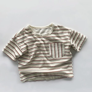Détail d'un t-shirt rayé en coton pour enfants avec poche poitrine en beige et olive