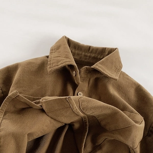Detailed close-up of brown brushed fabric kids shirt collar with tone-on-tone buttons