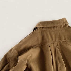 Detail of brown twill fabric texture, collar, and back pleat on children's retro shirt