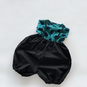 Flat lay of cotton kids' set with dark green polka dot shirt and black loose harem pants