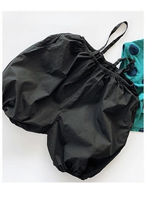 Flat lay of black bubble shorts with elastic waist and thin straps on white background