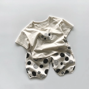 Détail d'un ensemble enfant en coton crème avec t-shirt smiley et short à pois