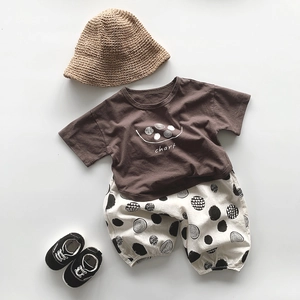 Ensemble d'été pour enfant avec t-shirt marron et pantalon à pois sur fond plat épuré